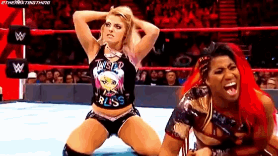 two women are wrestling in a ring and one is kneeling down .