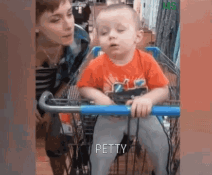 a baby is sitting in a shopping cart with a woman standing behind him .