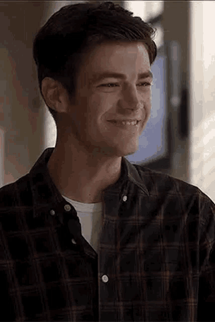 a man in a plaid shirt is smiling and looking at the camera .