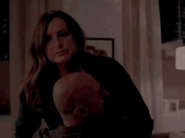 a woman is holding a bald man 's head in her arms