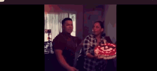 a man and woman are standing next to each other holding a birthday cake .