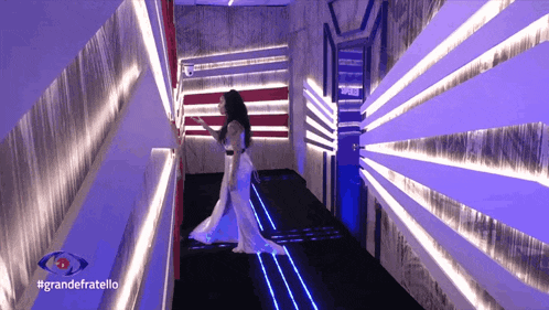 a woman in a long white dress is walking through a hallway with the hashtag grandefratello