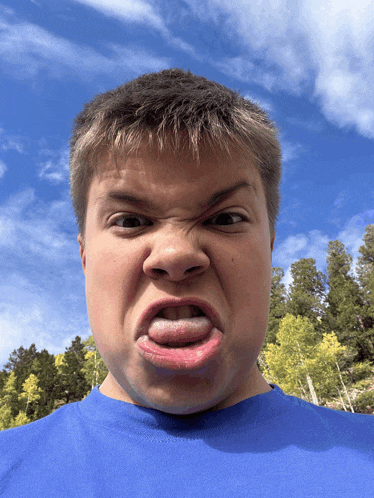 a boy in a blue shirt making a funny face