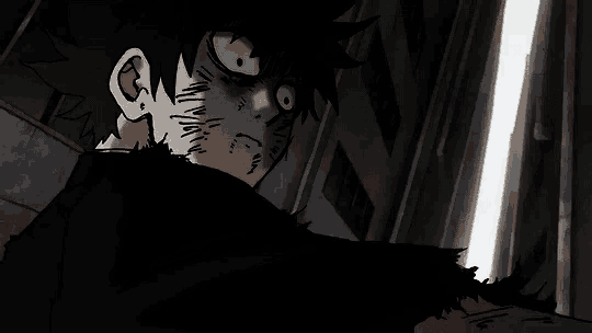 a close up of a person 's face in a dark room with a very angry look on their face .