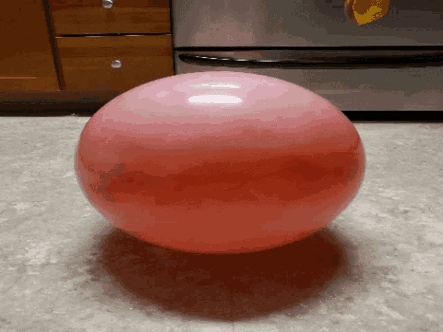 a pink balloon is sitting on a kitchen floor