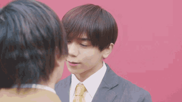 a man in a suit and tie is kissing another man on the cheek