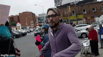 a man wearing glasses is walking down a street with a sign that says abc