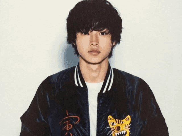 a young man is wearing a black jacket with a tiger on it