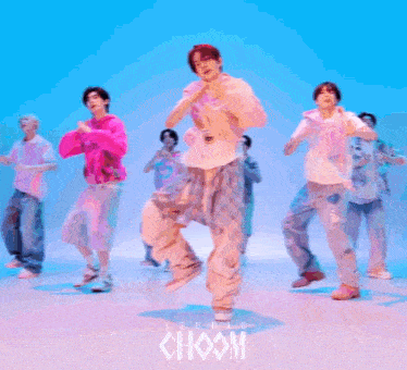 a group of young men are dancing in front of a blue sky and the word choom is visible