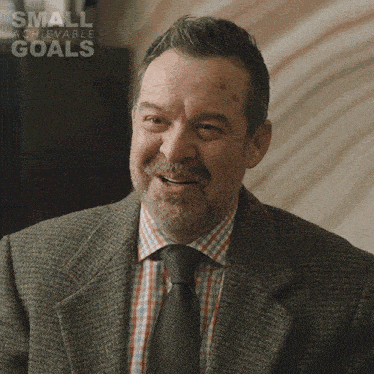 a man in a suit and tie is smiling in a small achievable goals advertisement