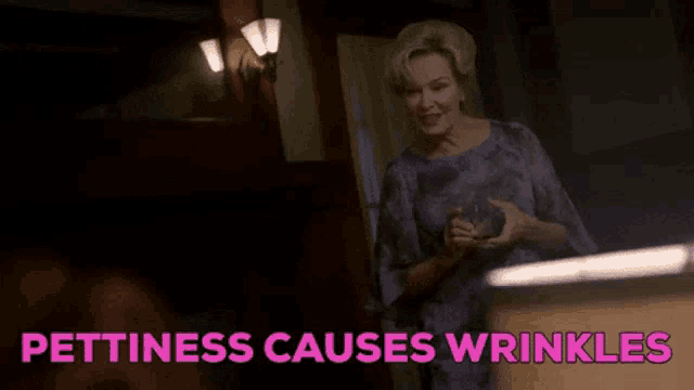 a woman in a purple dress is standing in a dark room with the words pettiness causes wrinkles .