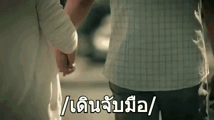 a man and a woman are holding hands while walking down a street .