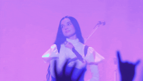 a woman is playing a guitar in front of a crowd