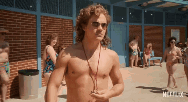 a shirtless man wearing sunglasses stands in front of a netflix ad