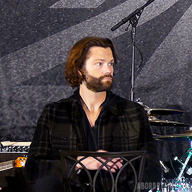 a man with a beard is sitting in front of a microphone with the word aboard in the corner