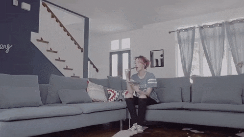 a woman sits on a couch in a living room with a sign on the wall that says " everyday "