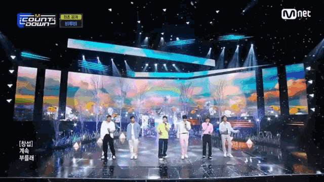 a group of people standing on a stage in front of a large screen that says mnet