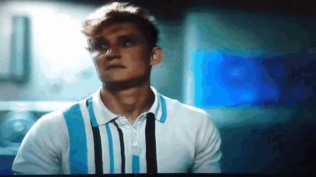 a man in a blue and white striped polo shirt is looking at something