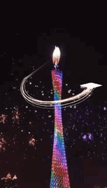 a picture of a man in a blue shirt is surrounded by fireworks and a rainbow colored candle .
