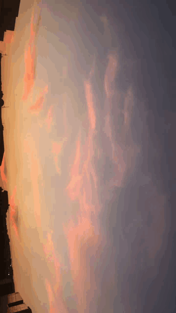 a sunset sky with pink clouds and a city in the background