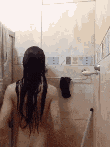 a naked woman with long hair is taking a shower in a bathroom