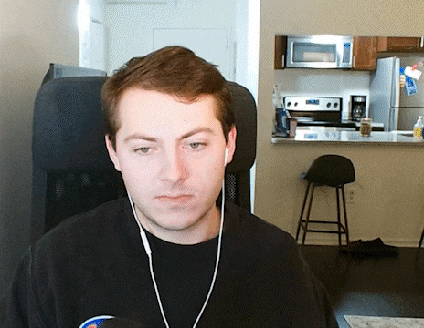 a man wearing headphones looks at the camera in front of a kitchen