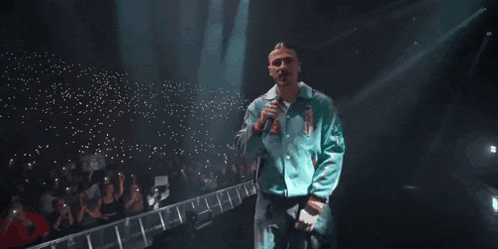 a man is singing into a microphone in front of a crowd .