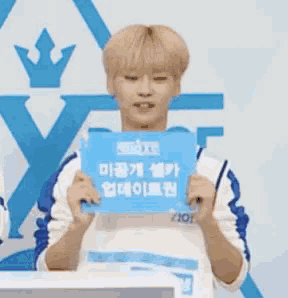 a young man with blonde hair is holding a blue sign that says ' a ' on it .
