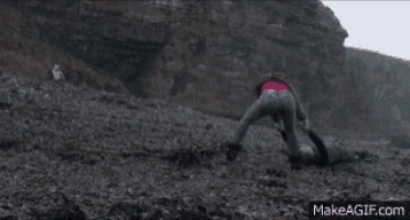 a woman is laying on the ground on a rocky beach .