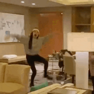 a woman is dancing in a living room in front of a couch and chairs .