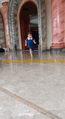 a little girl in a blue dress is running in a hallway with jangan lupa senyum yaa written on the floor