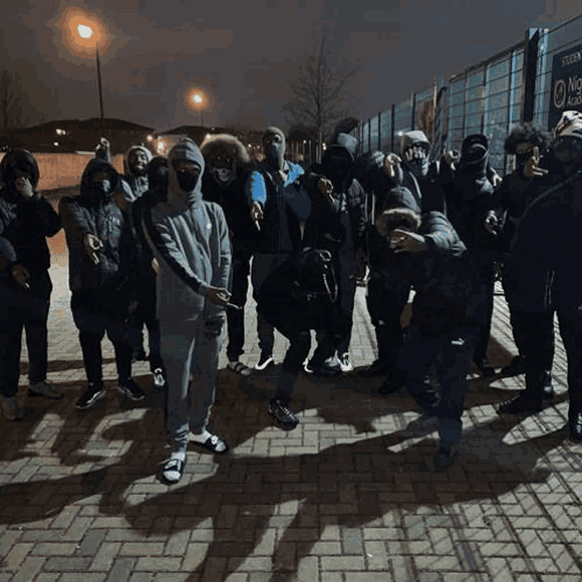 a group of people standing on a brick sidewalk with their faces covered