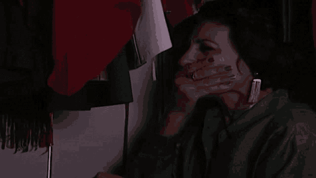 a woman covering her mouth with her hand while wearing earrings