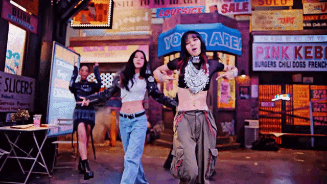 a group of women are dancing in front of a pink kebob restaurant