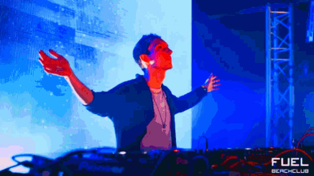 a man with his arms outstretched in front of a fuel beach club sign