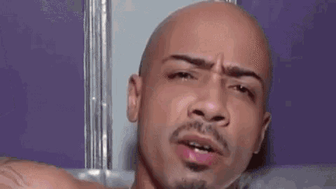 a bald man is having sex with a woman in a pink wig on a couch .