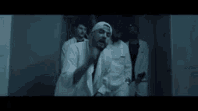 a group of men in white coats and hats are standing next to each other in a dark room .