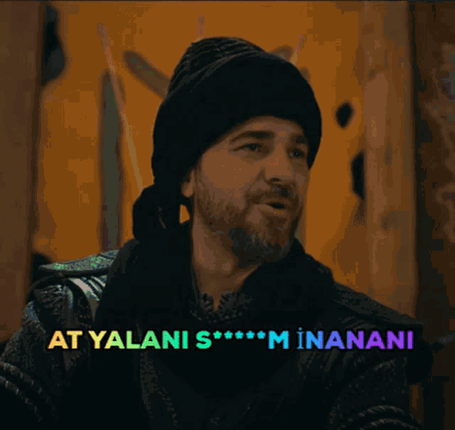 a man with a beard wearing a black hat and scarf with the words at yalani s *** m inananani above him