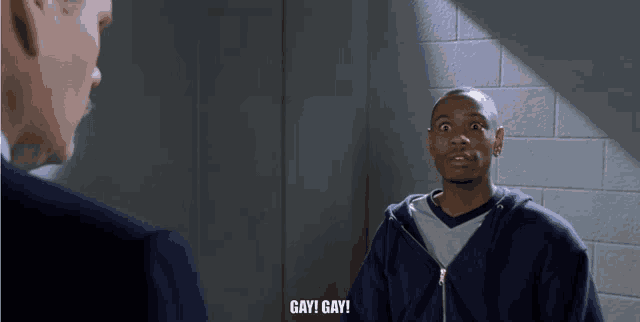 a man in a blue hoodie is talking to another man and says gay gay