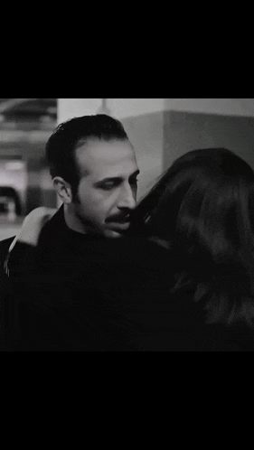 a man and a woman are hugging in a black and white photo .