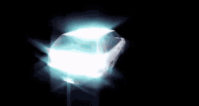 a close up of a light shining in the dark with a black background .
