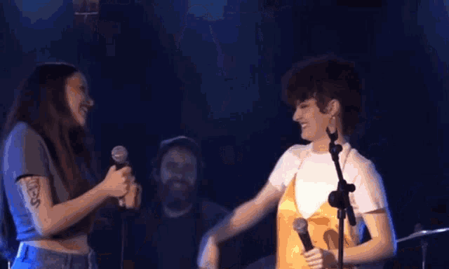 a group of people are hugging on a stage in front of a microphone that says ' yamaha ' on it