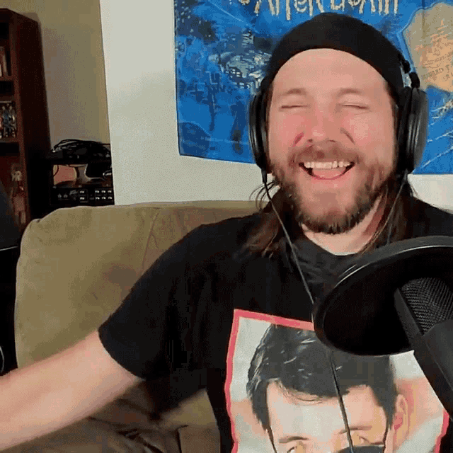 a man wearing headphones and a black shirt with a picture of a man on it is smiling