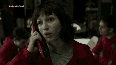 a woman in a red jacket is talking on a cell phone in a dark room .