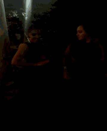 a couple of women standing next to each other in the dark