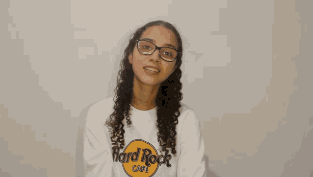 a woman wearing glasses and a hard rock cafe sweatshirt smiles