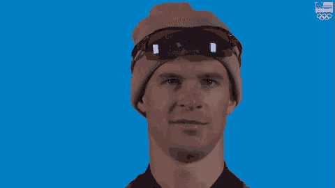 a man wearing a beanie and sunglasses making a funny face .