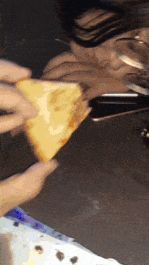 a person eating a slice of pizza with a glass of water