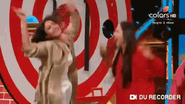two women are dancing in front of a red and white circle .
