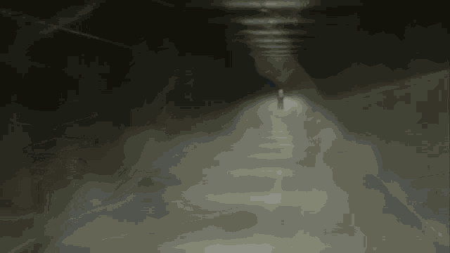 a man in a white shirt is walking through a tunnel